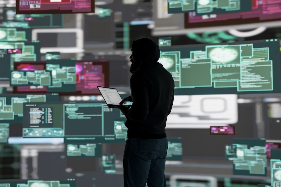 Conceptual representation of cyber crime with male hacker exploiting system vulnerability, using programming technique and surveillance to override digital defenses and leak information.